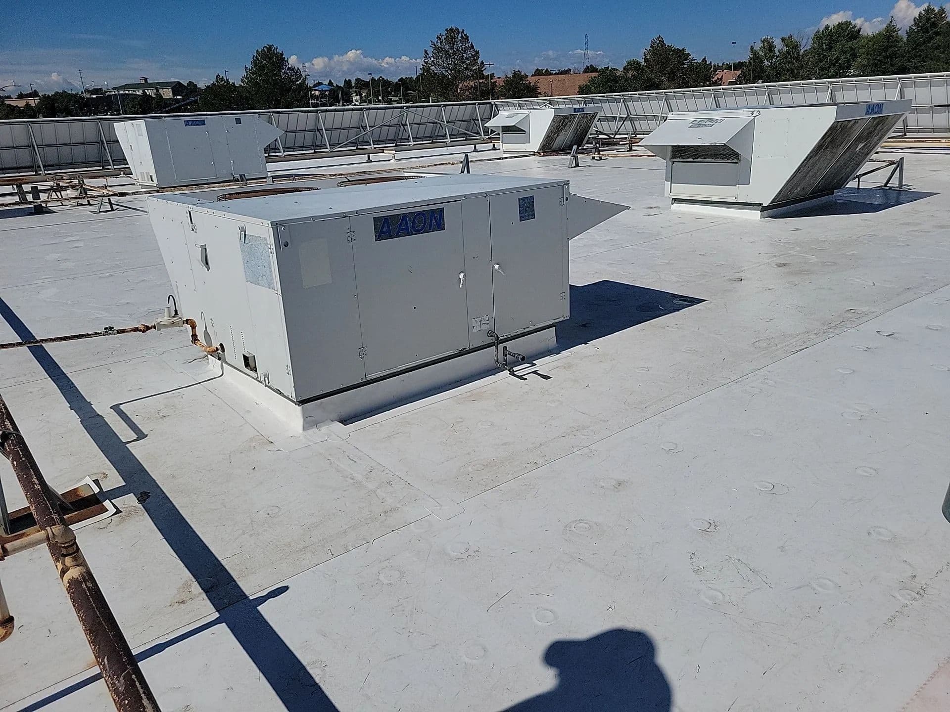 Rooftop HVAC units on a white membrane roof with new flashing at their curbs
